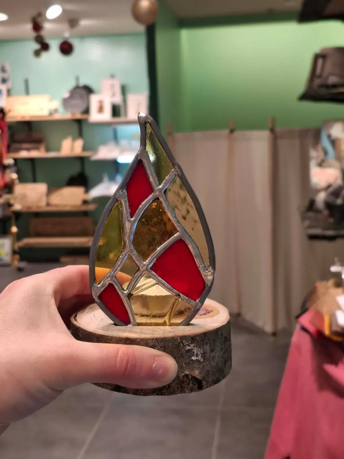 Photophore artisanal en vitrail flamme aux verres rouge, jaune et ambré monté sur socle rond en bois.
