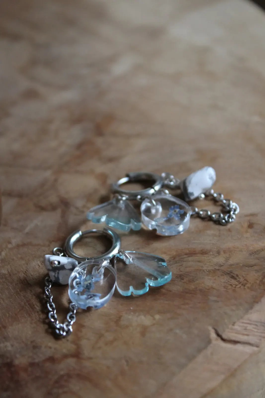 Paire de boucles d'oreilles créoles posée à plat sur un support en bois clair.
