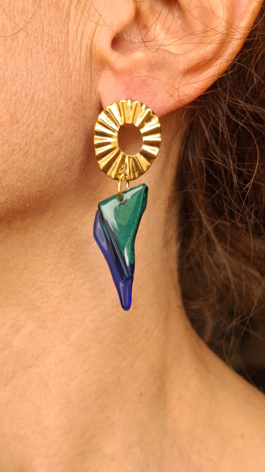 Boucle d'oreille portée avec puce ronde dorée et pendentif asymétrique en verre bleu et vert