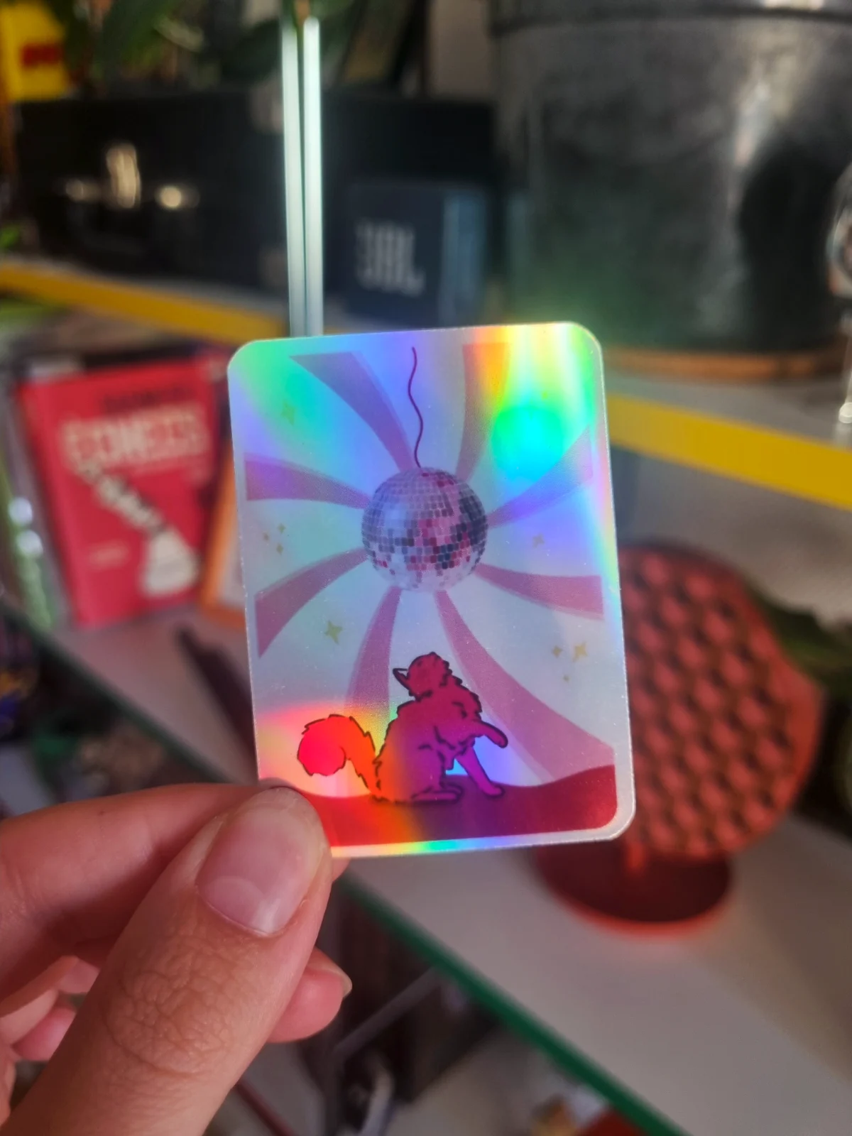 Sticker holographique rectangulaire avec un chat sous une boule disco et des reflets irisés
