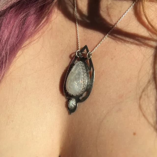 Vue de trois-quarts du pendentif gothique en argent serti de peristerite porté au cou