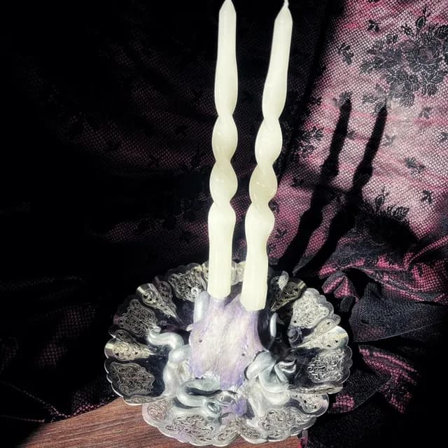Vue du dessus du bougeoir violet et argenté avec deux bougies torsadées claires sur coupelle ciselée.