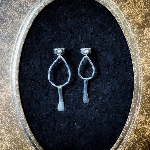 Gros plan sur les boucles d'oreilles Aliénor argentées, montées sur puces avec anneaux ajourés texturés