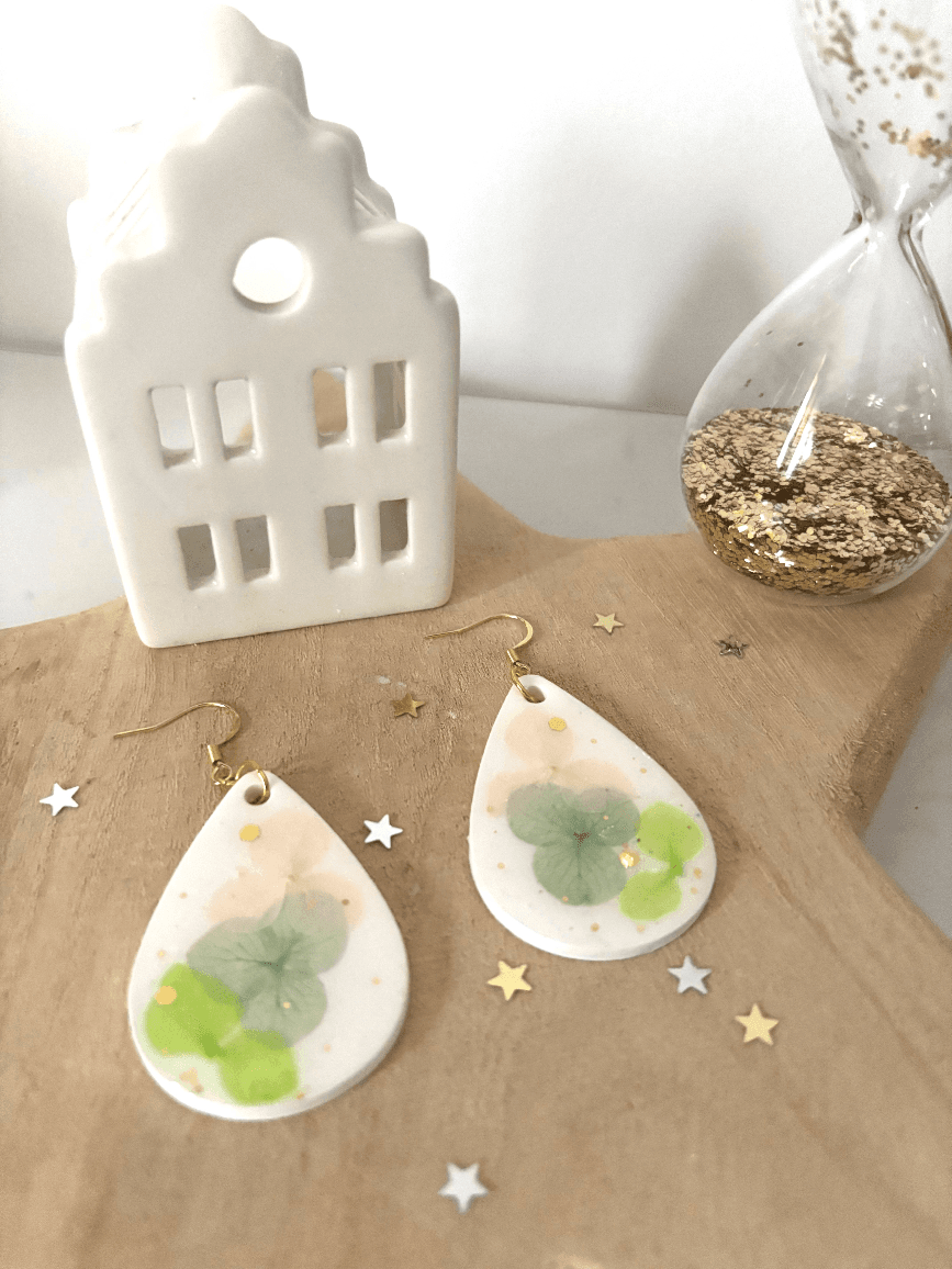 Paire de boucles d'oreilles Bucolique sur support en bois avec décor de maisonnette blanche.