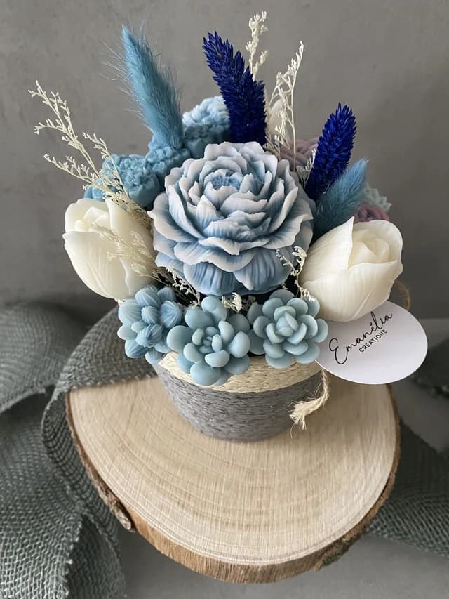 Bouquet de fondants fleurs bleu pastel et blanches dans un pot tressé posé sur un rondin de bois