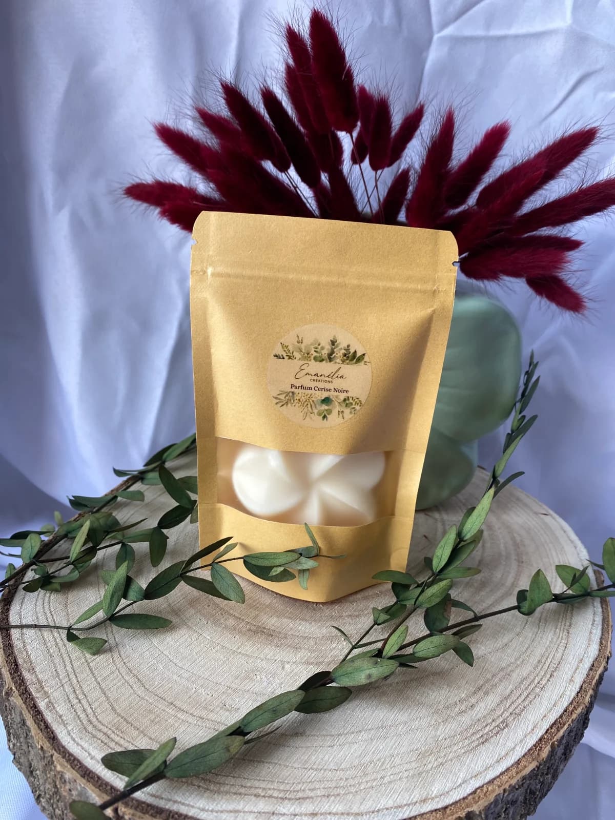 Sachet kraft avec étiquette ronde présentant un fondant parfumé blanc en forme de fleur.
